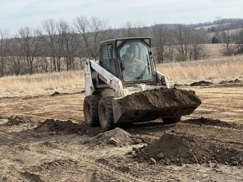 Skid steer moving dirt on a job site
